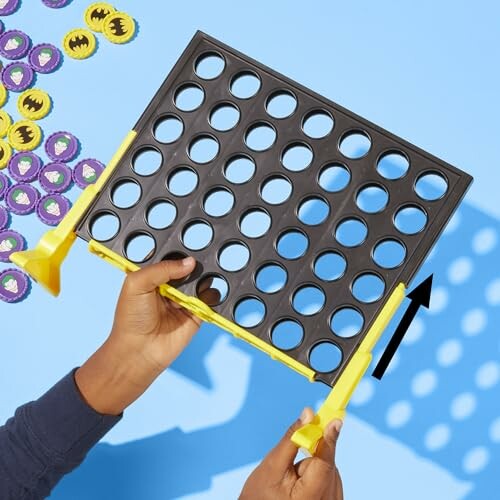 Hands assembling a Batman-themed Connect Four game with tokens.