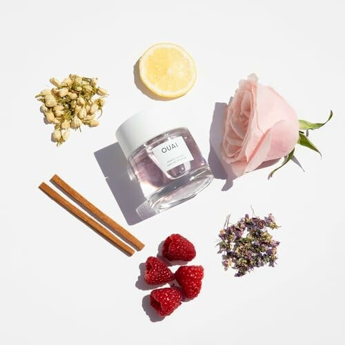 Beauty product surrounded by a lemon slice, pink rose, cinnamon sticks, raspberries, and small flowers.