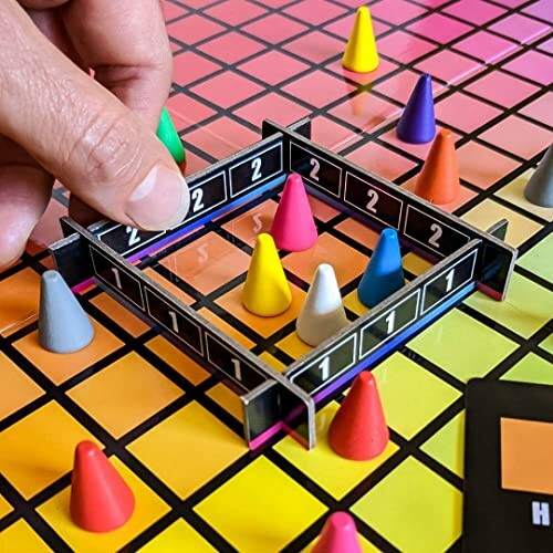 Close-up of a hand moving a piece in a colorful board game with cones.