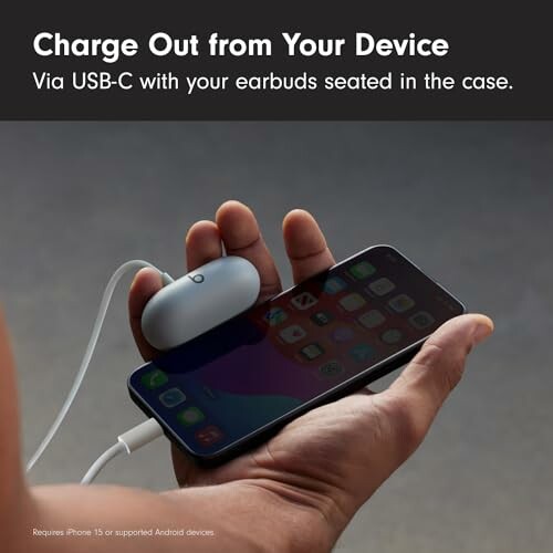 Person holding a smartphone charging earbuds via USB-C.