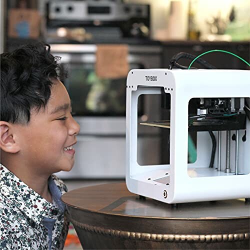 Child watching a 3D printer in action on a table.