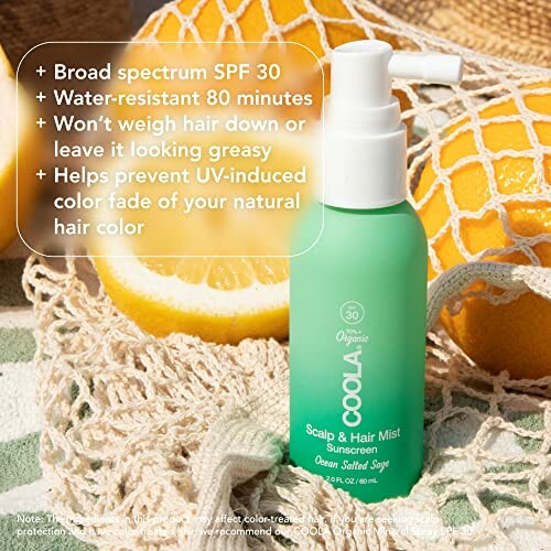 COOLA Scalp and Hair Mist SPF 30 beside a sliced lemon and beach towel.