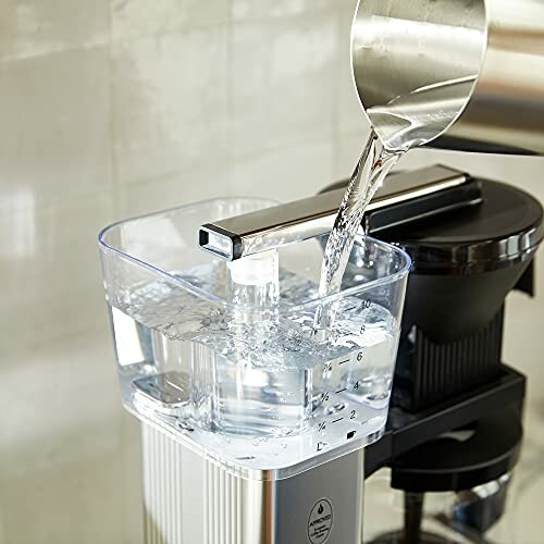 Water being poured into a coffee machine's reservoir.