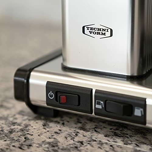 Close-up of a coffee maker base with buttons on a countertop.