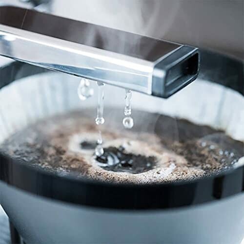 Close-up of a coffee maker dripping water onto coffee grounds.