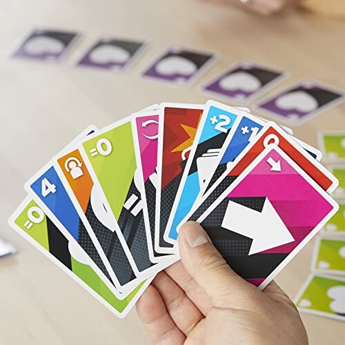 Hand holding colorful playing cards in a game setting.