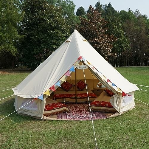 Cozy bell tent with colorful bunting in a grassy field.