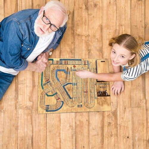 Two people playing a cribbage board game on wooden floor.