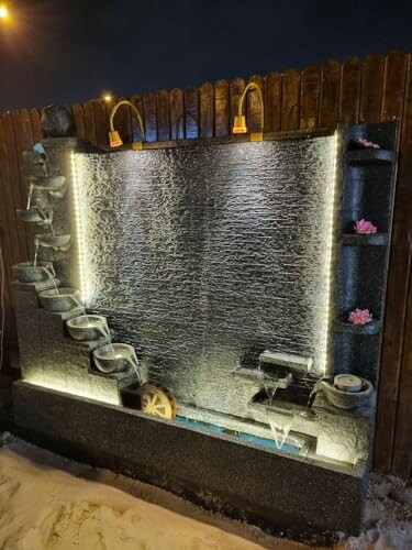 Illuminated decorative water fountain with cascading bowls at night