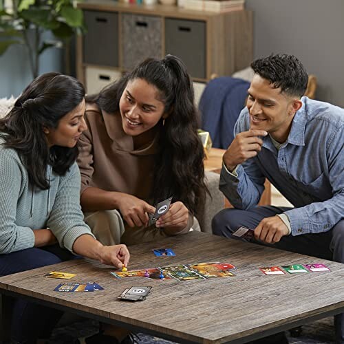 Three friends playing a card game at a table, smiling and engaged.