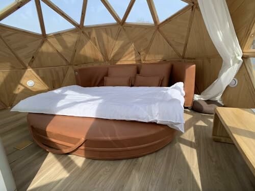 Interior of a geodesic dome with a round bed and wooden panels.