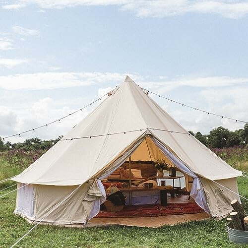 Bell tent with cozy interior and string lights in a field.