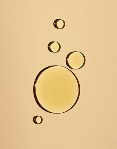 Golden oil droplets on a beige background