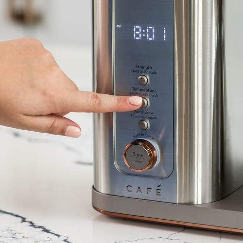 Hand pressing buttons on a coffee machine display.