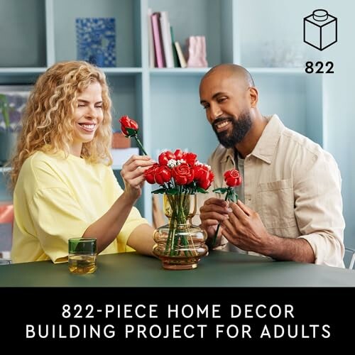 Two adults assembling a home decor project with red flowers.