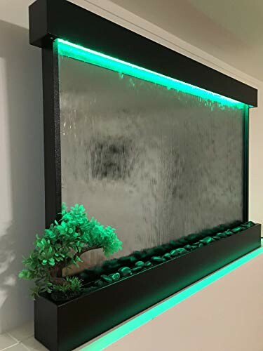 Indoor water wall with green lighting and small plant decoration.