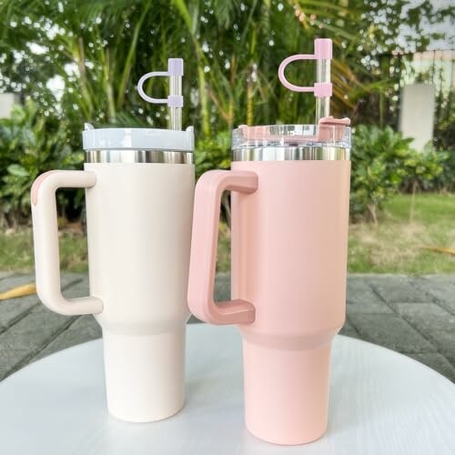 Two insulated tumblers with handles on a table outdoors