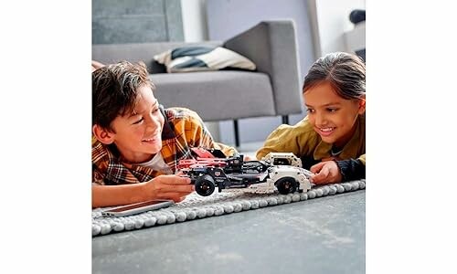 Two children playing with a LEGO car on the floor.