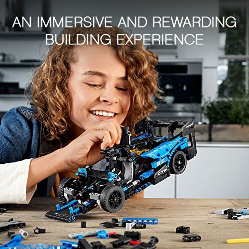 Person assembling a blue and black LEGO car model.