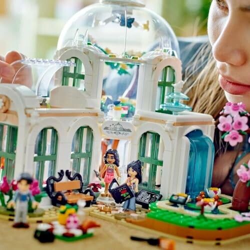 Child playing with LEGO figures in a miniature building set.