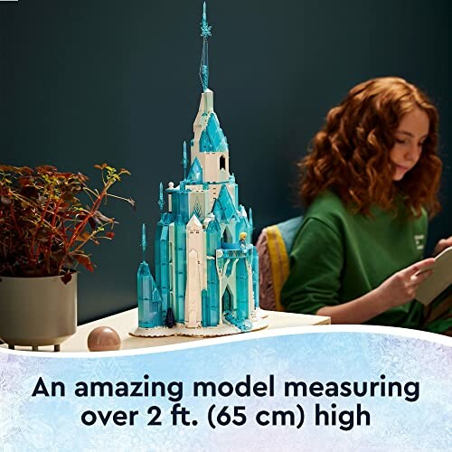 Large LEGO ice castle model with person reading nearby.