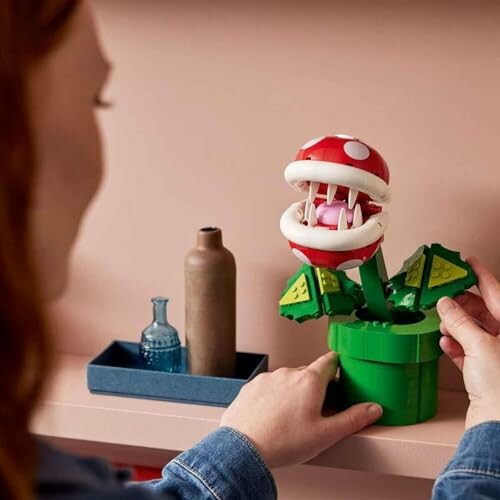 Person arranging a LEGO Piranha Plant model on a shelf.