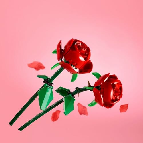 Two LEGO roses with scattered petals on a pink background