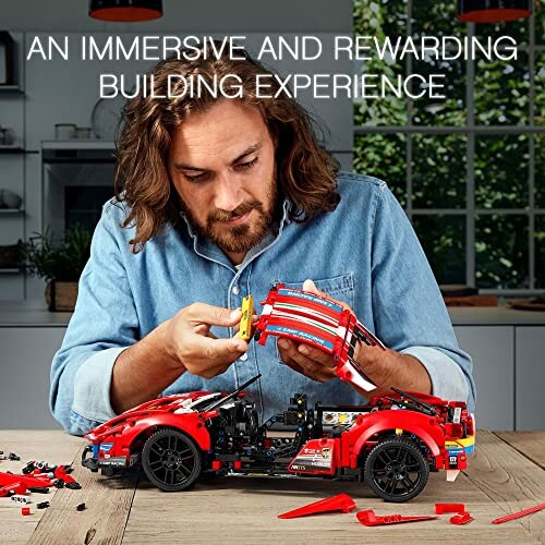 Man assembling a red LEGO car model on a table.