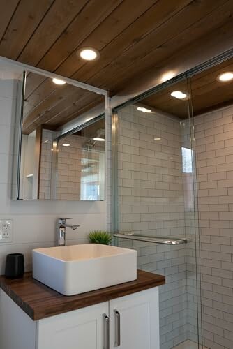 Modern bathroom with wooden ceiling, square sink, and glass shower.