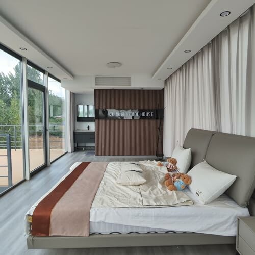 Modern bedroom with large windows, bed, and balcony view.