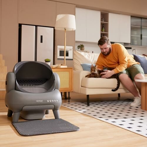 Man with cat near modern litter box in living room.