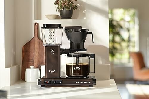 Modern coffee maker on a kitchen counter with sunlight.