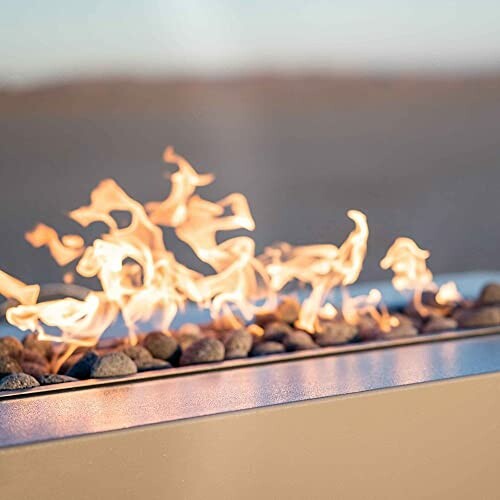 Close-up of a modern fire pit with flames and rocks.