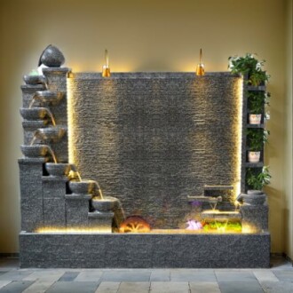 Modern indoor water fountain with cascading bowls and plants.