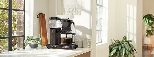 Modern kitchen with coffee maker on countertop near window.