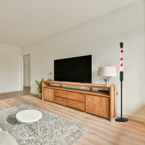 Modern living room with TV, wooden console, and floor lamp.