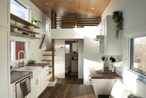 Interior view of a modern tiny house with wood accents and white cabinets.