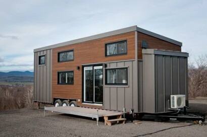 Modern tiny house with wood paneling and large windows.