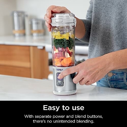 Person using a Ninja blender with vegetables inside.