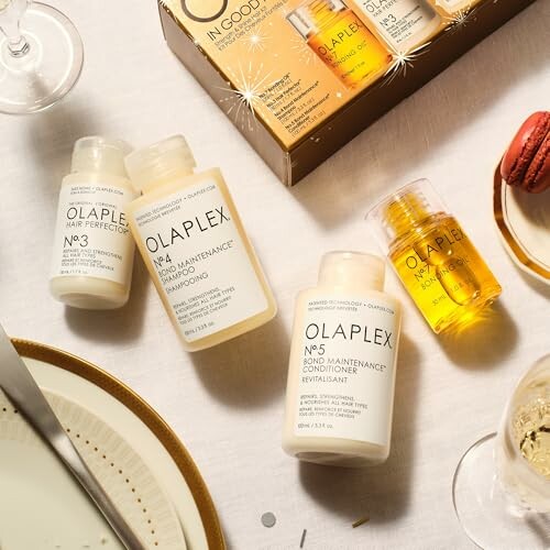 Olaplex hair care products on a table with wine glasses and a macaron.