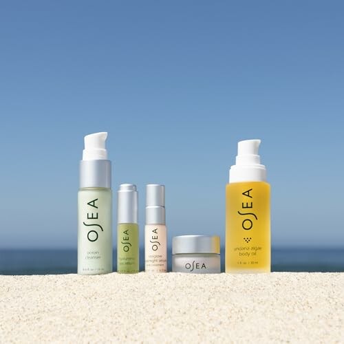 OSEA skincare products displayed on sand with a clear sky background.