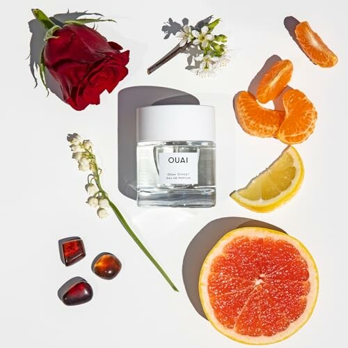 OUAI fragrance bottle surrounded by citrus slices, rose, and flowers.