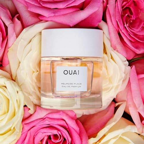 Ouai perfume bottle nestled among pink and white roses