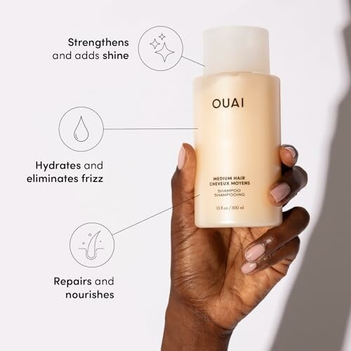 Hand holding Ouai medium hair shampoo bottle with benefits highlighted.