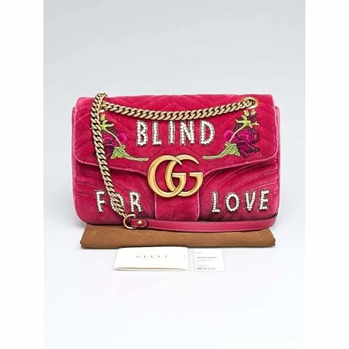 Pink designer handbag with chain and 'Blind for Love' text