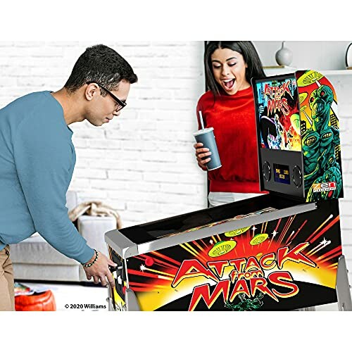 Two people playing Attack from Mars pinball machine.