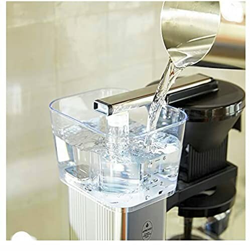 Water being poured into a coffee machine reservoir.