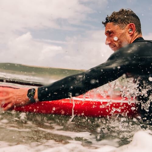 Man surfing in the ocean with a red surfboard