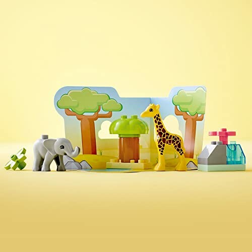 Toy zoo set with giraffe, elephant, and trees on yellow background