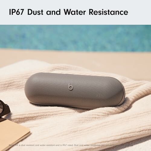 Wireless speaker on towel by pool, IP67 dust and water resistance.